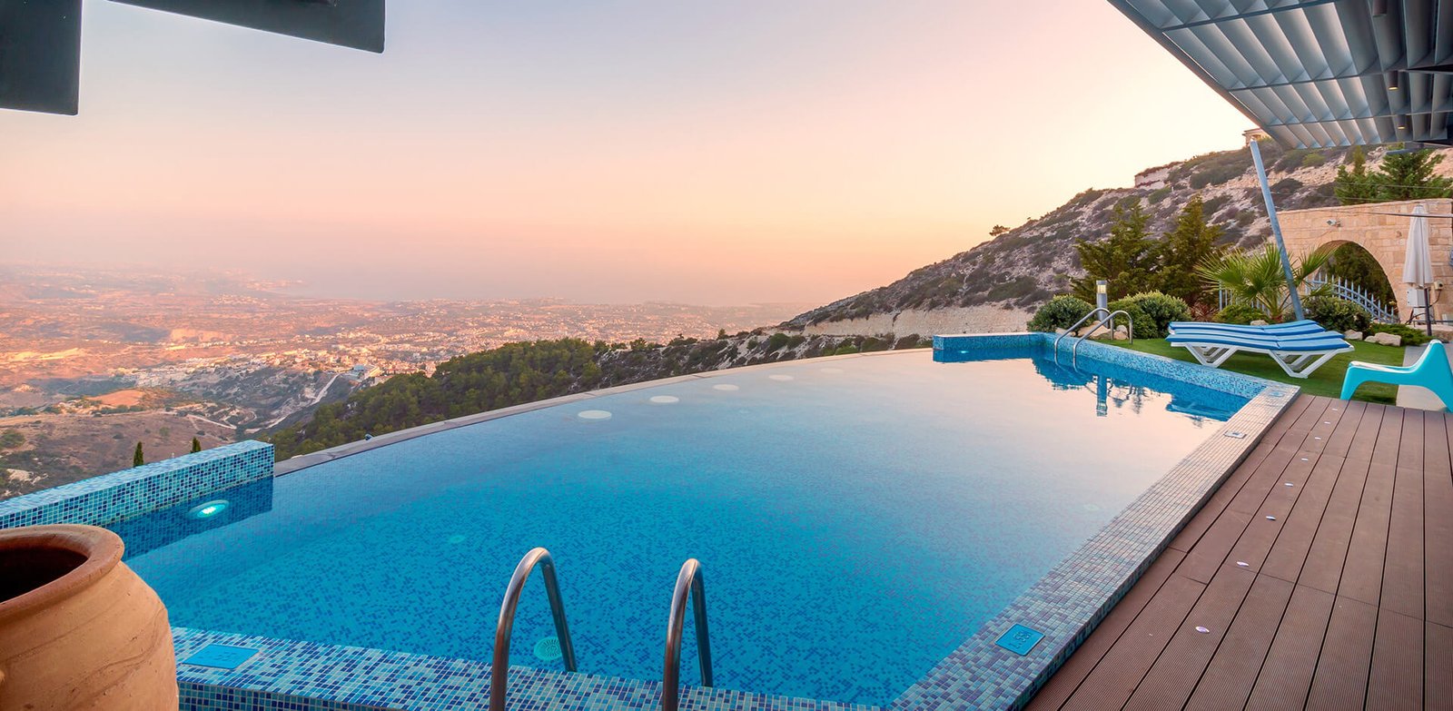 infinity pool overlooks a scenic hilltop view at sunset
